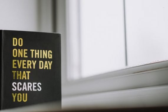 Rectangular shaped book with printed title on black hardcover on windowsill in house in daytime